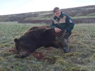 Hunter holds the paw of an Alaska Peninsula Brown Bear